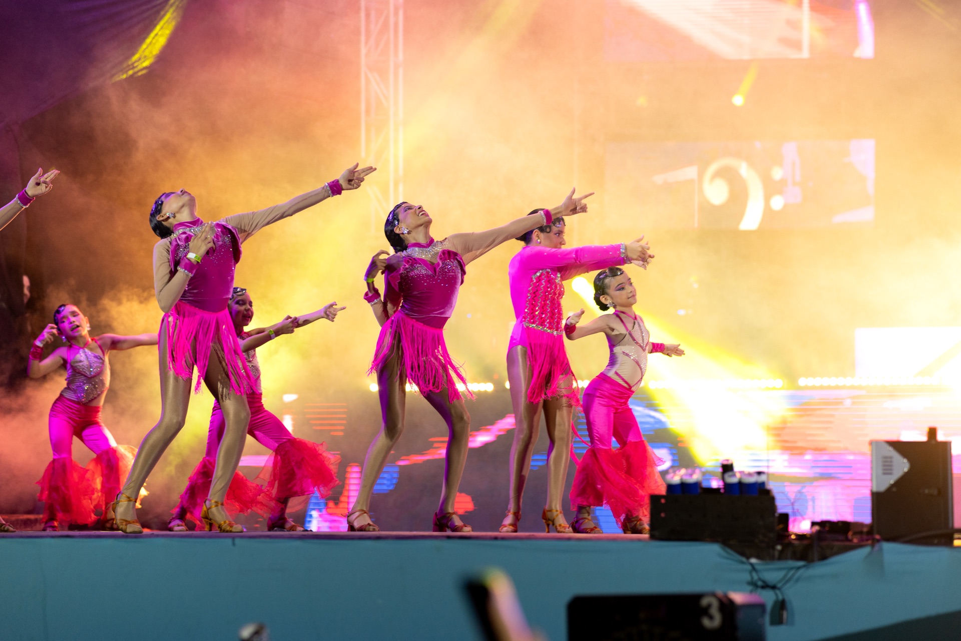 Niñas bailando en escenario con trajes rosa